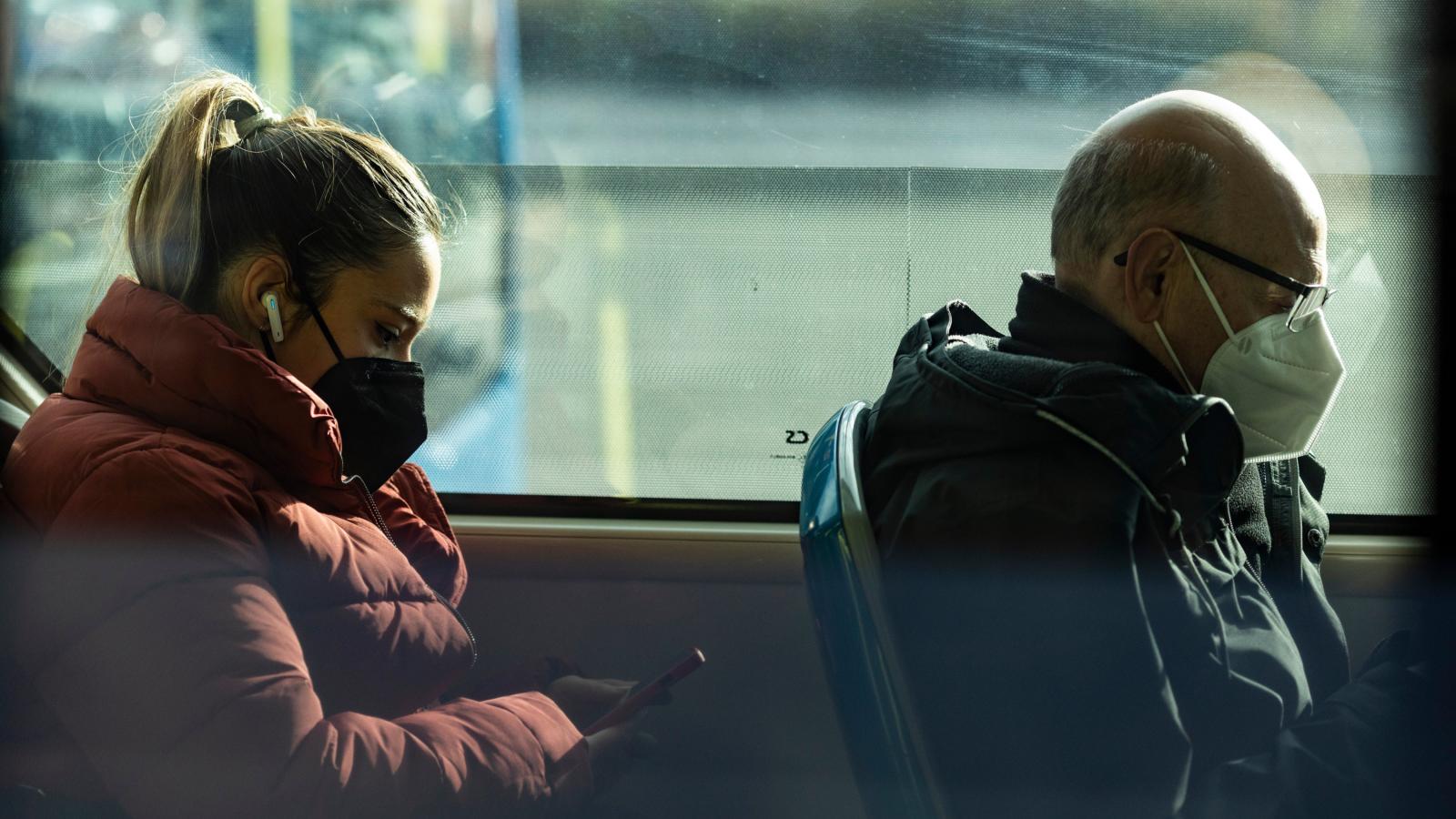 Dos personas con mascarillas viajan en un transporte público