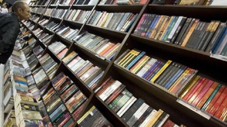 Un hombre ojea varios libros en una librería