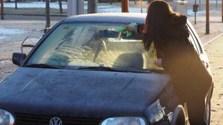 Imagen de archivo de una mujer quitando el hielo de su coche