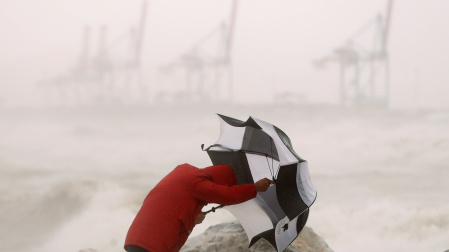 Imagen de archivo de una persona refugiándose del fuerte viento y las precipitaciones