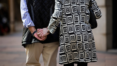 Imagen de una pareja de personas mayores de espaldas cogidos de la mano paseando