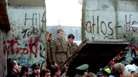 East German border guards look through a hole in the Berlin Wall after demonstrators pulled down the segment at Brandenburg Gate in Berlin, in this Nov. 11, 1989.