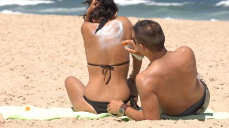 Jóvenes poniéndose crema solar en la playa