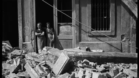 Fotografía de dos mujeres que observan los efectos de un bombardeo en el barrio de la Barceloneta de Barcelona, en 1937