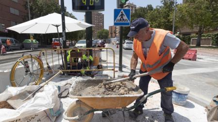 Un trabajador de la construcción junto a un termómetro que marca cuarenta grados en la avenida de la Fama de Murcia.