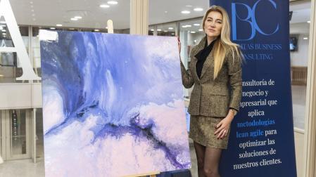 La artista Elena Ksanti junto a su obra "Nacimiento del mundo" de la serie "Mundos paralelos"