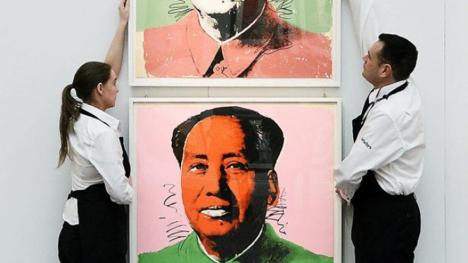 Dos trabajadores colocan el retrato de Mao del artista Andy Warhol