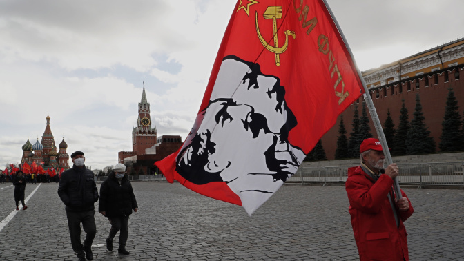 Un partidario del partido comunista ruso sostiene una bandera con retratos de los líderes comunistas Stalin y Lenin después de la ceremonia de colocación de flores en el mausoleo de Lenin (Rusia, Moscú) EFE/EPA/MAXIM SHIPENKOV