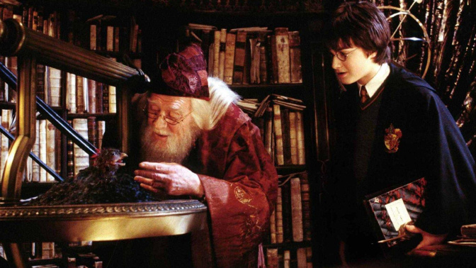 El actor Daniel Radcliffe (R) interpreta a Harry Potter mientras observa cómo el Profesor Dumbledore, interpretado por el fallecido Richard Harris, alimenta a Fawkes, el Fénix, en  "Harry Potter y la cámara secreta"